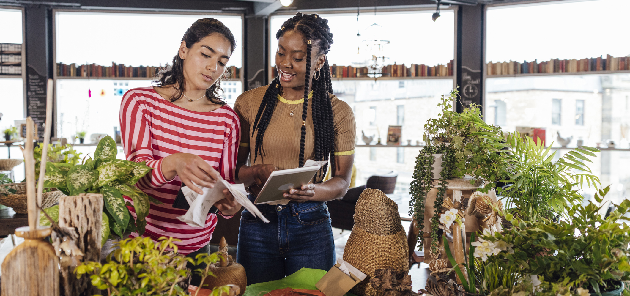 Two women working in a plant shop/greenhouse